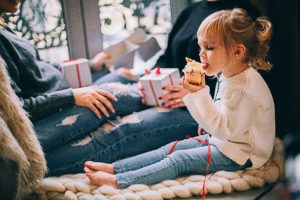 Little girl eating a cupcake at a holiday gathering.