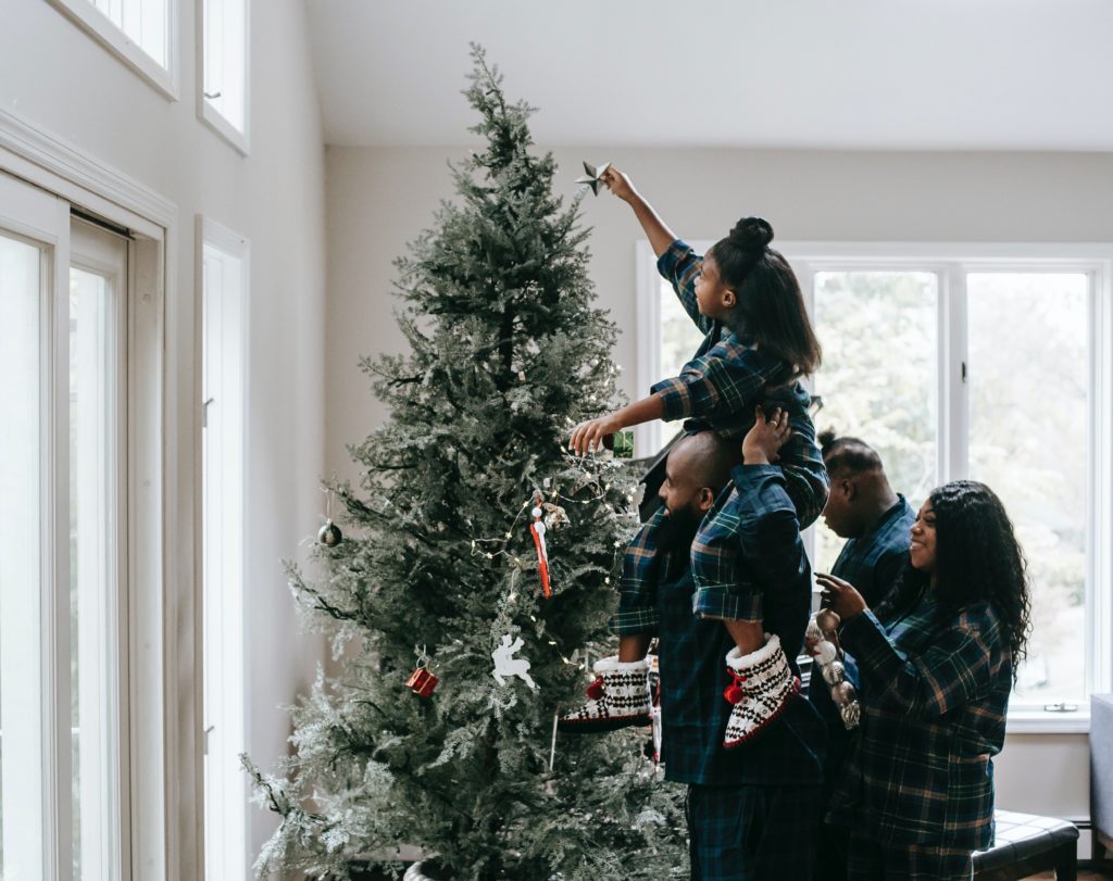Family with matching pajamas decorating a Christmas tree together. 